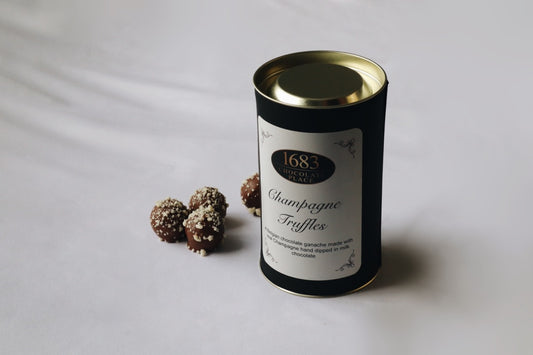 Elegant packaging of Champagne Truffles with chocolate truffles beside it, showcasing a luxurious treat.
